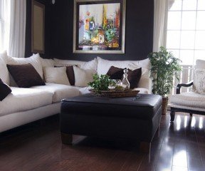 New Uses living room with dark wood floor, white couch with dark-grey pillows, dark curtains, white and wood side chair, dark wood coffee table